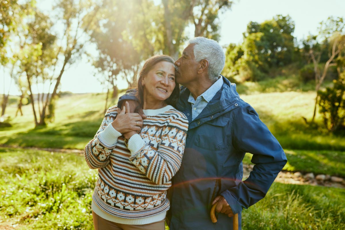 An older couple embracing outside