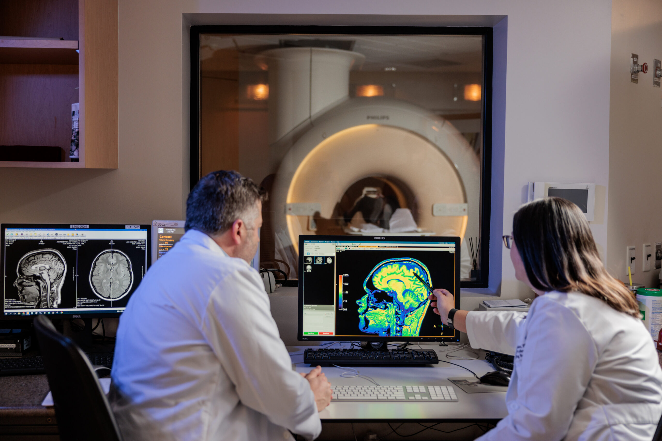 Two doctors sitting, looking at monitor with brain scan